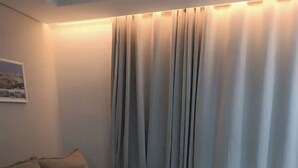 A corner living room with a beige sofa, a small table, and a wall-mounted picture. - 1 Near Confins Airport, Cid Galo, 15 min BH, Cid Adm.  (Centro Vespasiano)