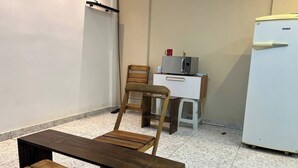 Una pequeña kitchenette equipada con microondas, refrigerador y una silla de madera.