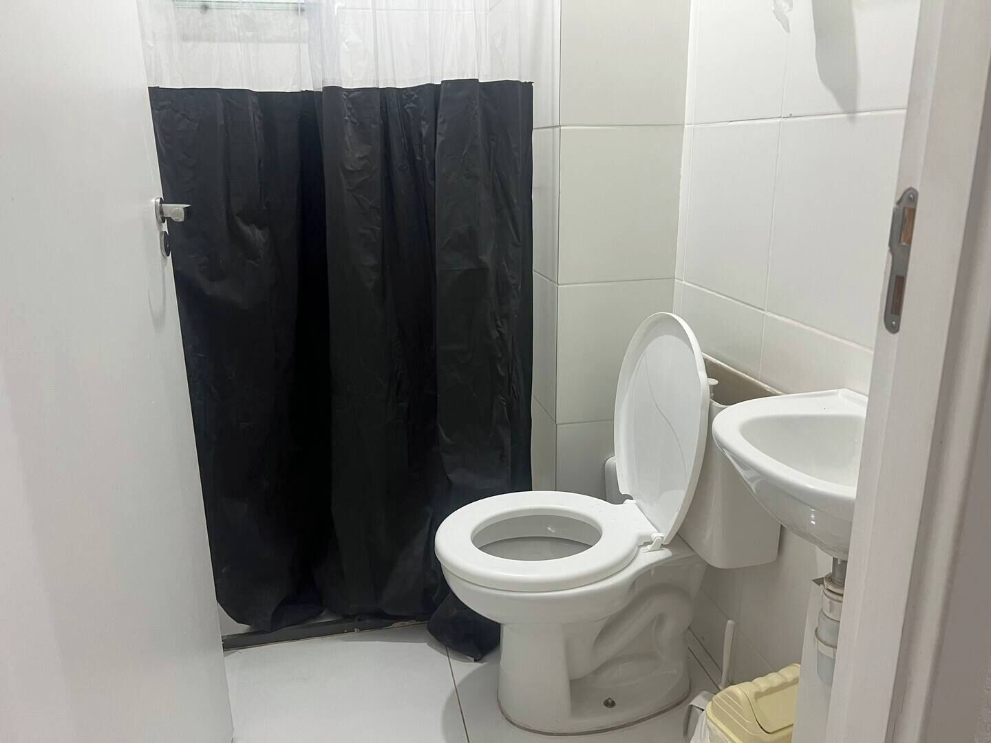 Ein kleines Badezimmer mit Toilette, Waschbecken und Duschvorhang.