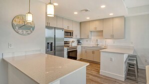 A modern kitchen with white cabinetry, stainless steel appliances, and a large island. - NEW! Waterfront Luxury in Sarasota – Near Downtown & Beaches! (Sarasota)