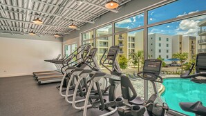 A gym with treadmills and a pool area, large windows, and a view of the cityscape. - NEW! Waterfront Luxury in Sarasota – Near Downtown & Beaches! (Sarasota)