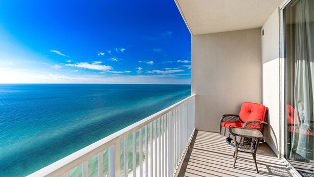 A balcony with a view of the ocean, a wicker chair, and a red cushion. - *Aug 29 - Sept 2 Open * End of Summer Getaway!* (Panama City Beach)