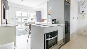 A modern kitchen with a built-in oven, a refrigerator, and a coffee machine. - WI-FI 500mb | 65" Smart TV | Pool #CAMP10 (Florianópolis)