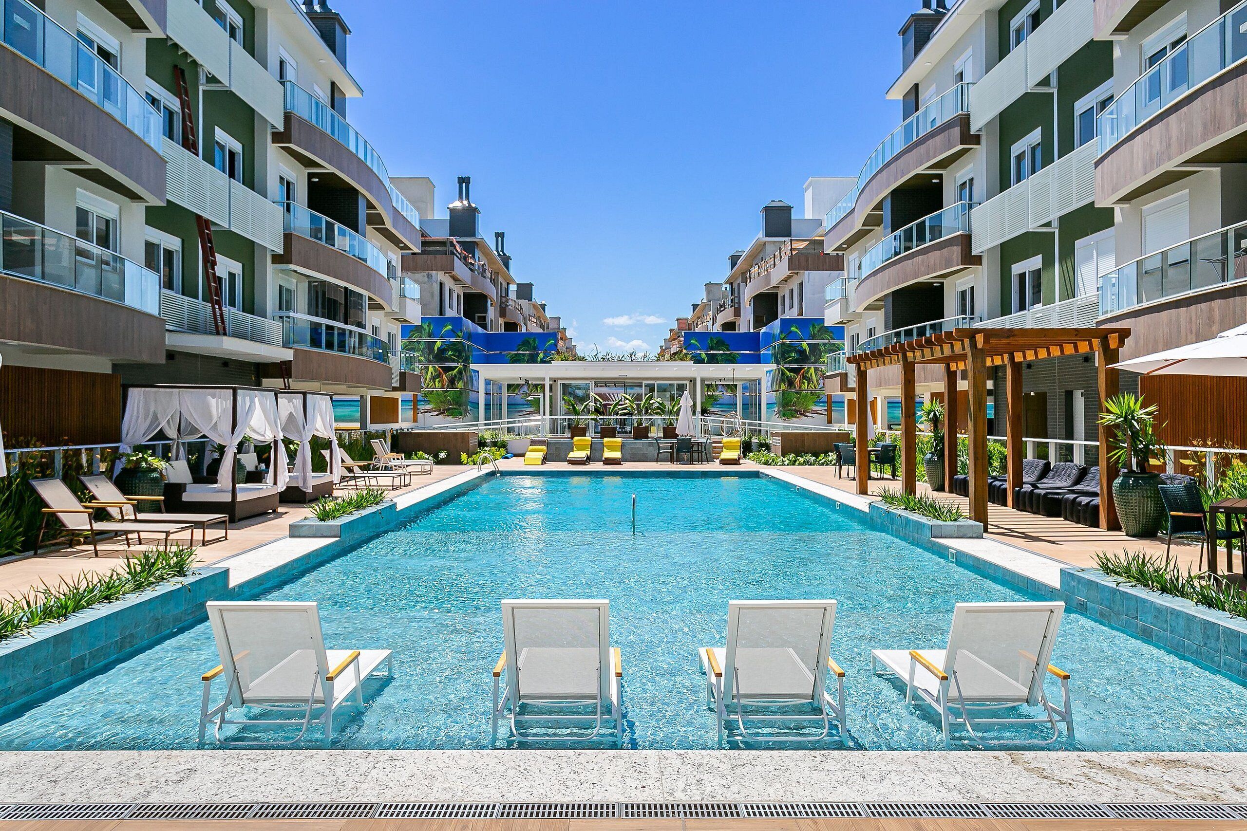 Piscina com espreguiçadeiras, área de estar coberta e vista para edifícios altos.