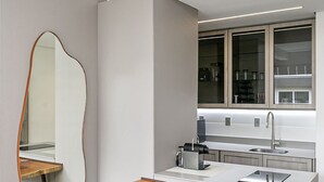 A modern kitchen with a central island, a large mirror, and two wooden chairs. - WI-FI 500mb | 65" Smart TV | Pool #CAMP10 (Florianópolis)