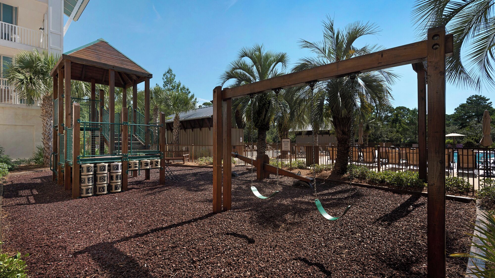A playground with swings, a climbing structure, and a covered seating area.