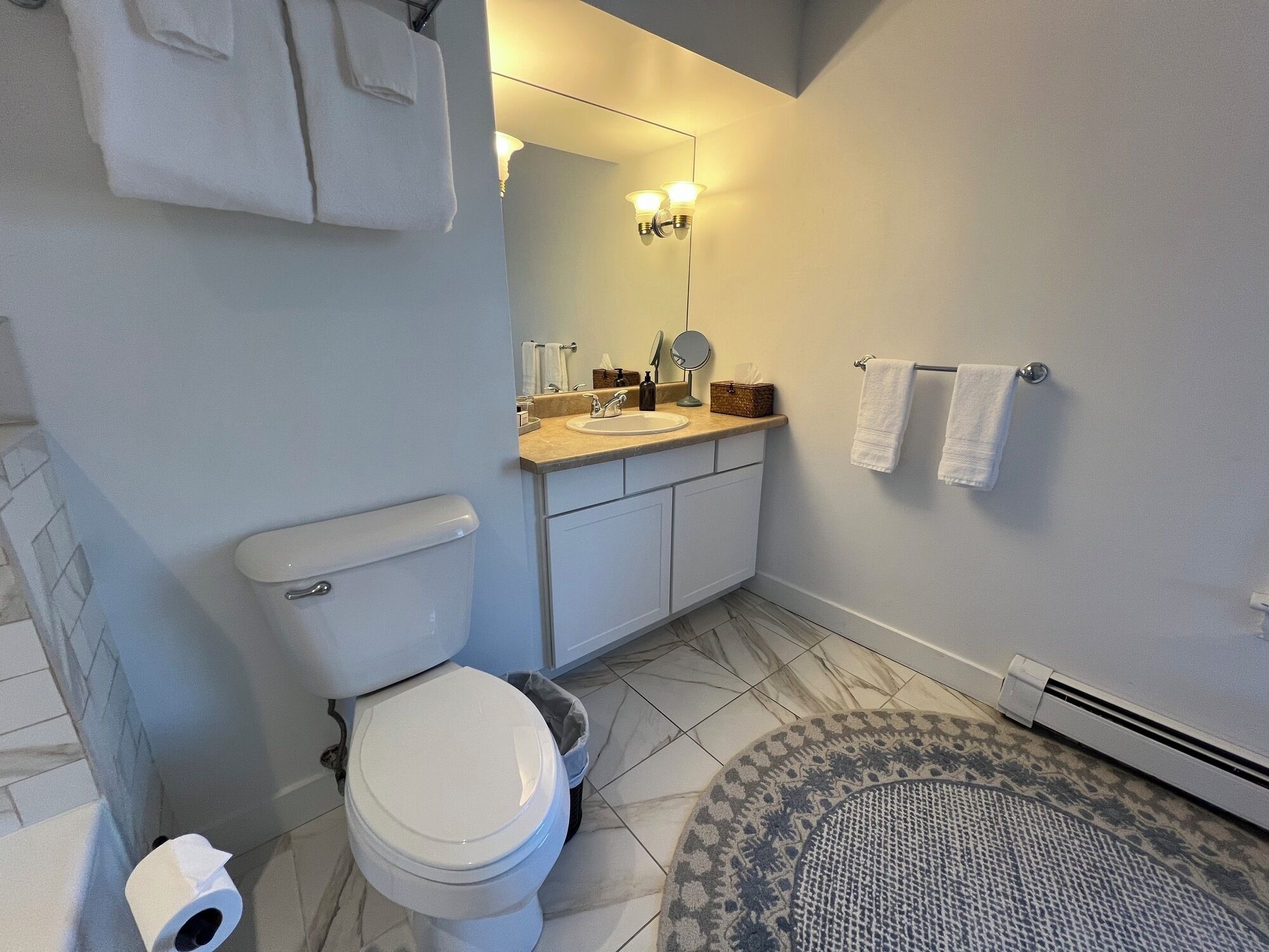 A bathroom with a toilet, sink, mirror, and towel rack.