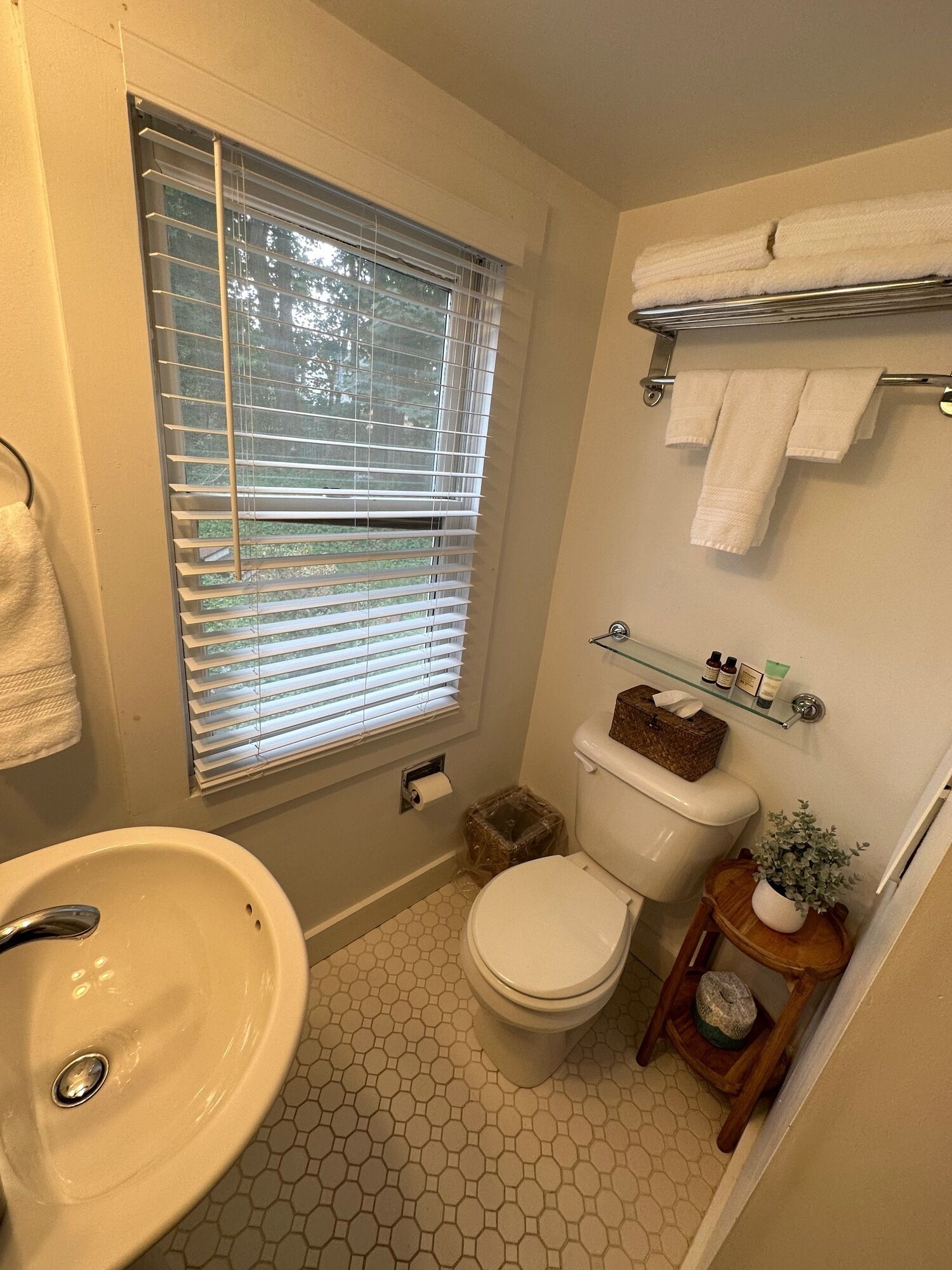 Un baño con inodoro, lavamanos y ventana con persianas.