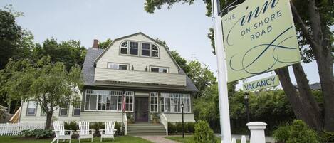 A two-story house with a porch, a sign indicating 'The Inn on Shore Road' and 'Vacancy'.
