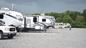 A gravel parking area with RVs and a truck. - Walk to ROCK THE SOUTH RV Camping with Generator 4 Night Package Cullman Alabama (Cullman)