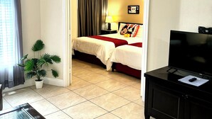 Une chambre d’hôtel avec un lit, une télévision, une plante et un bureau.