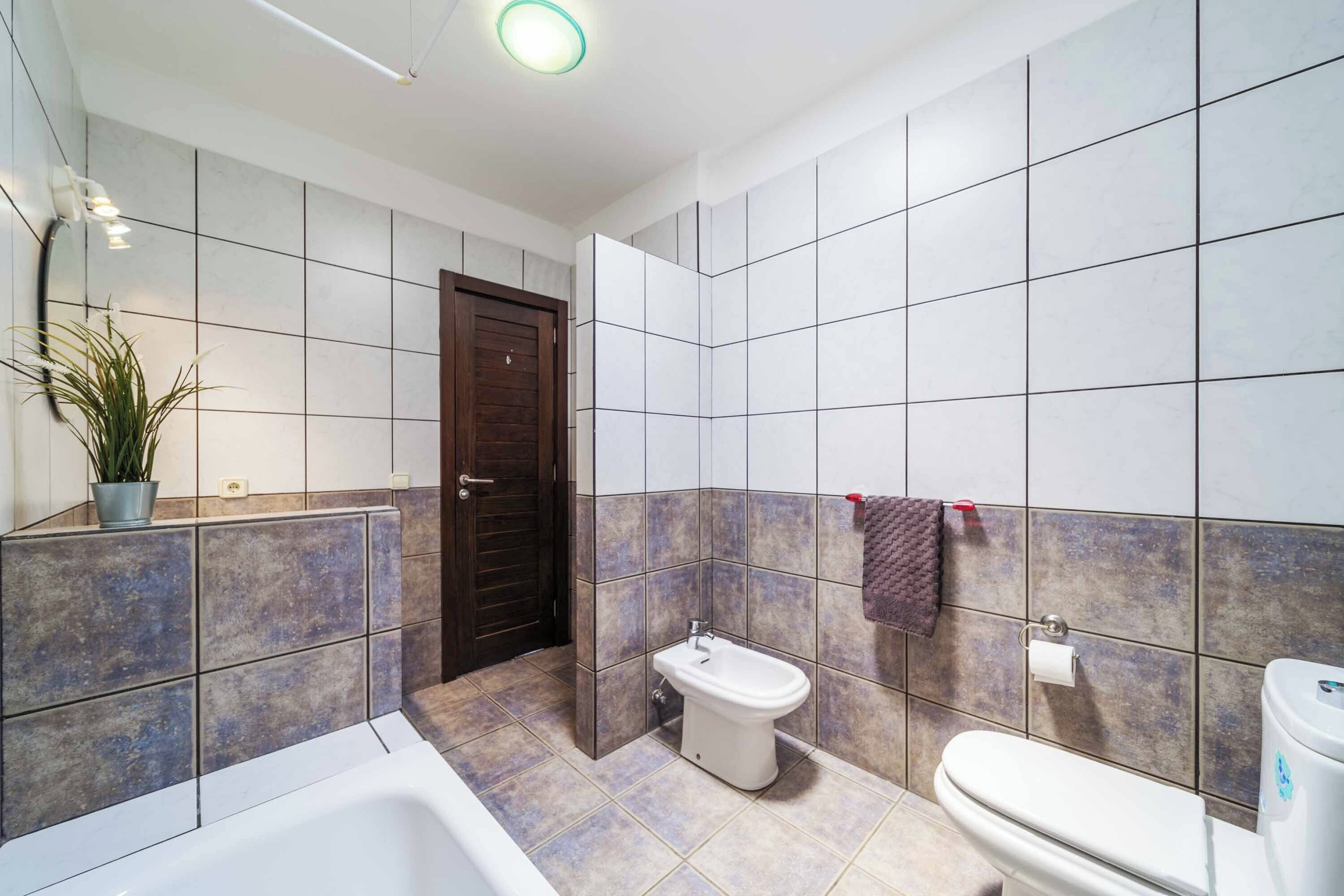 A modern bathroom with a bathtub, toilet, and bidet.