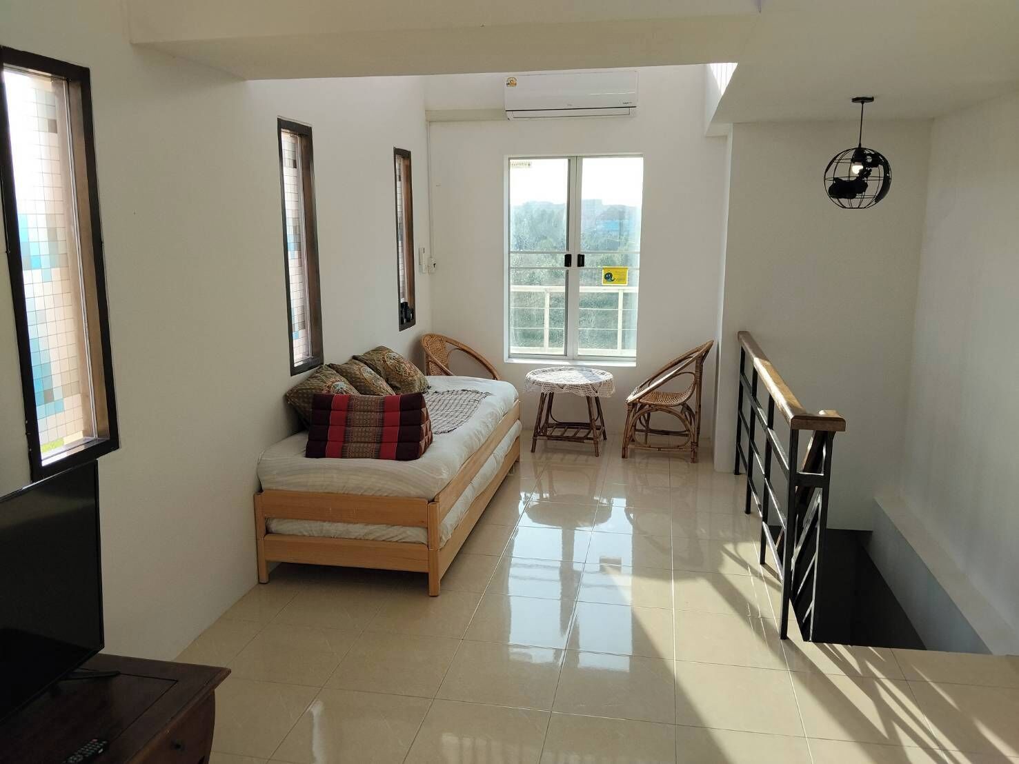 A room with a bed, a TV, a window, a table, and a chair.
