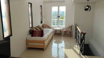 A room with a bed, a TV, a window, a table, and a chair.