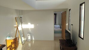Ruime kamer met dakraam, een houten dressoir, bureau en een bed op de achtergrond.