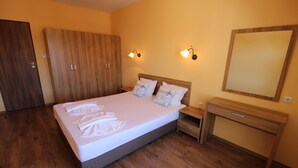 Un dormitorio con cama, armario de madera, mesita de noche y espejo.
