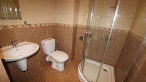 Un baño con lavamanos, inodoro y ducha con cerramiento de vidrio.