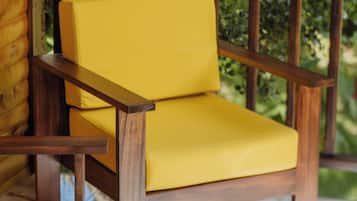 A yellow chair with wooden armrests and legs, placed on a tiled floor.