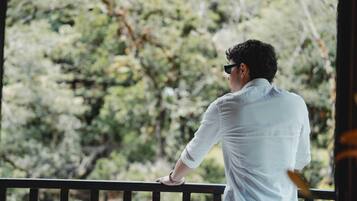 Una persona de pie en un balcón con vistas a árboles.