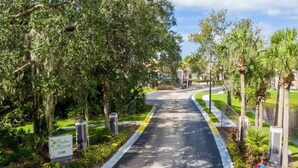 Une route menant à une zone fermée par des portails, avec un panneau indiquant « Palms Resort » et le numéro 3100.