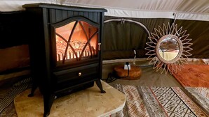 Una habitación acogedora con una estufa de leña, una cesta tejida y un espejo decorativo.