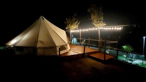 Alojamiento con carpa, terraza de madera y luces colgantes.