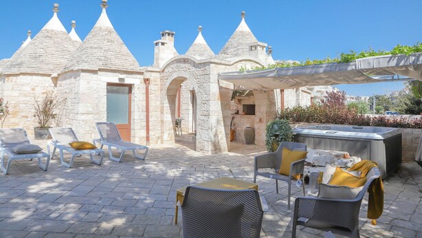 An outdoor seating area with stone buildings, a hot tub, and lounge chairs. - Country Trullo Rosso With Jacuzzi Alberobello (Alberobello)