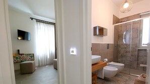 Un bany modern amb plat de dutxa de vidre, vàter i rentapans.