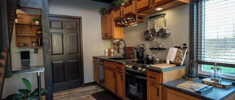 A kitchen with wooden cabinets, a stove, and a window with blinds.