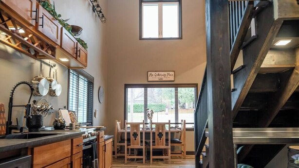 Une cuisine avec des meubles en bois, un coin repas avec une table et des chaises, et un escalier.