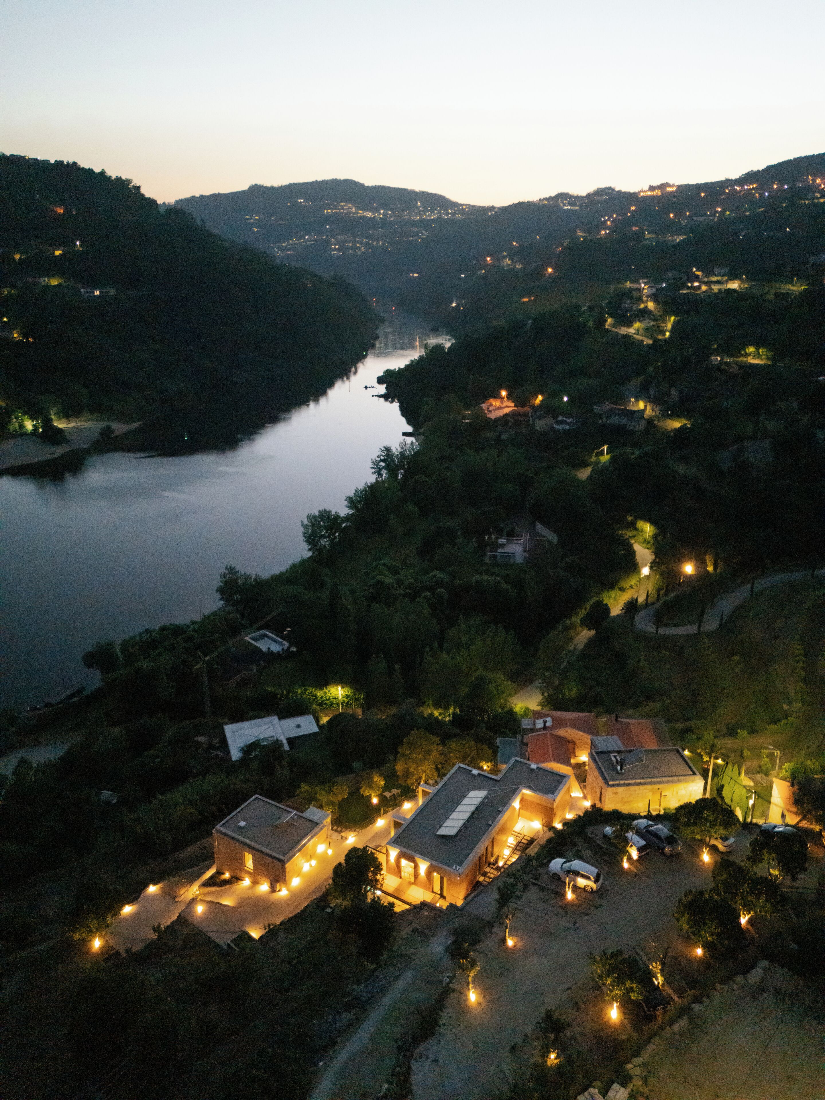 Vue aérienne d’un quartier résidentiel avec des maisons, une rivière et des collines environnantes.