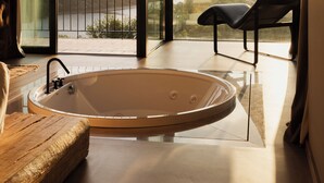 A modern bathroom with a freestanding bathtub, a wooden bench, and a view of a river and mountains through large glass doors. - Dajas Douro Valley – New opening (Marco de Canaveses)