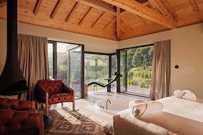 Un dormitorio moderno con un ventanal grande, una bañera y una zona de estar acogedora.