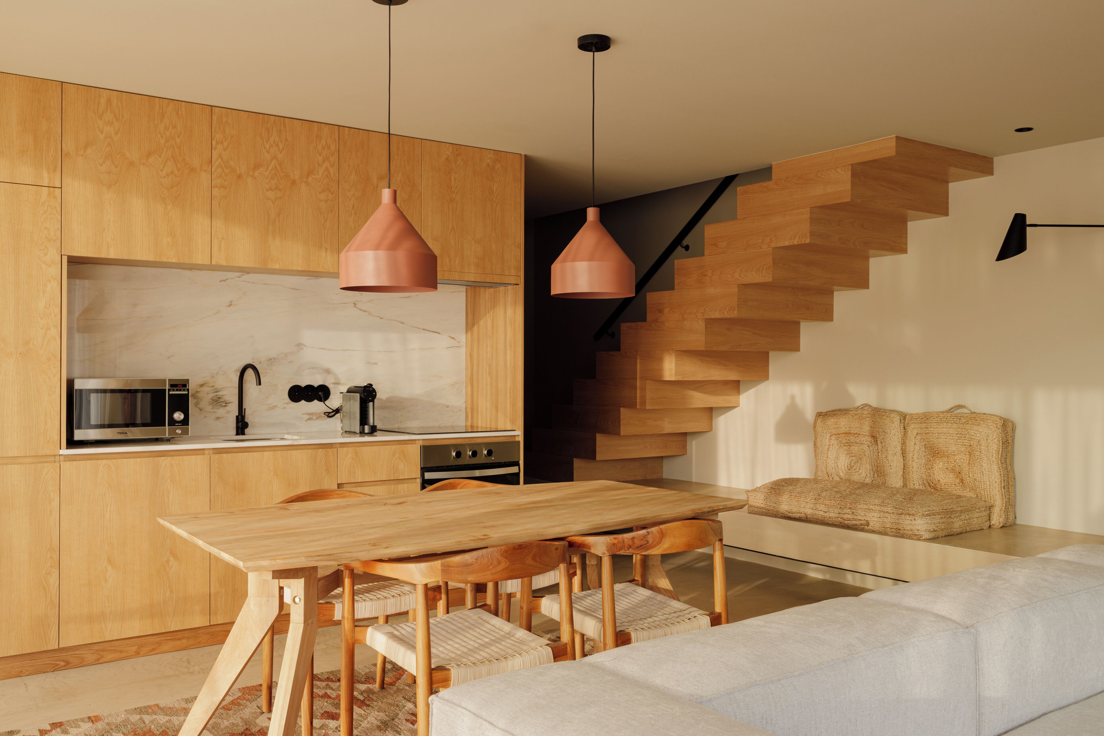 Una cocina moderna con armarios de madera, un microondas integrado y un comedor con mesa y sillas de madera.