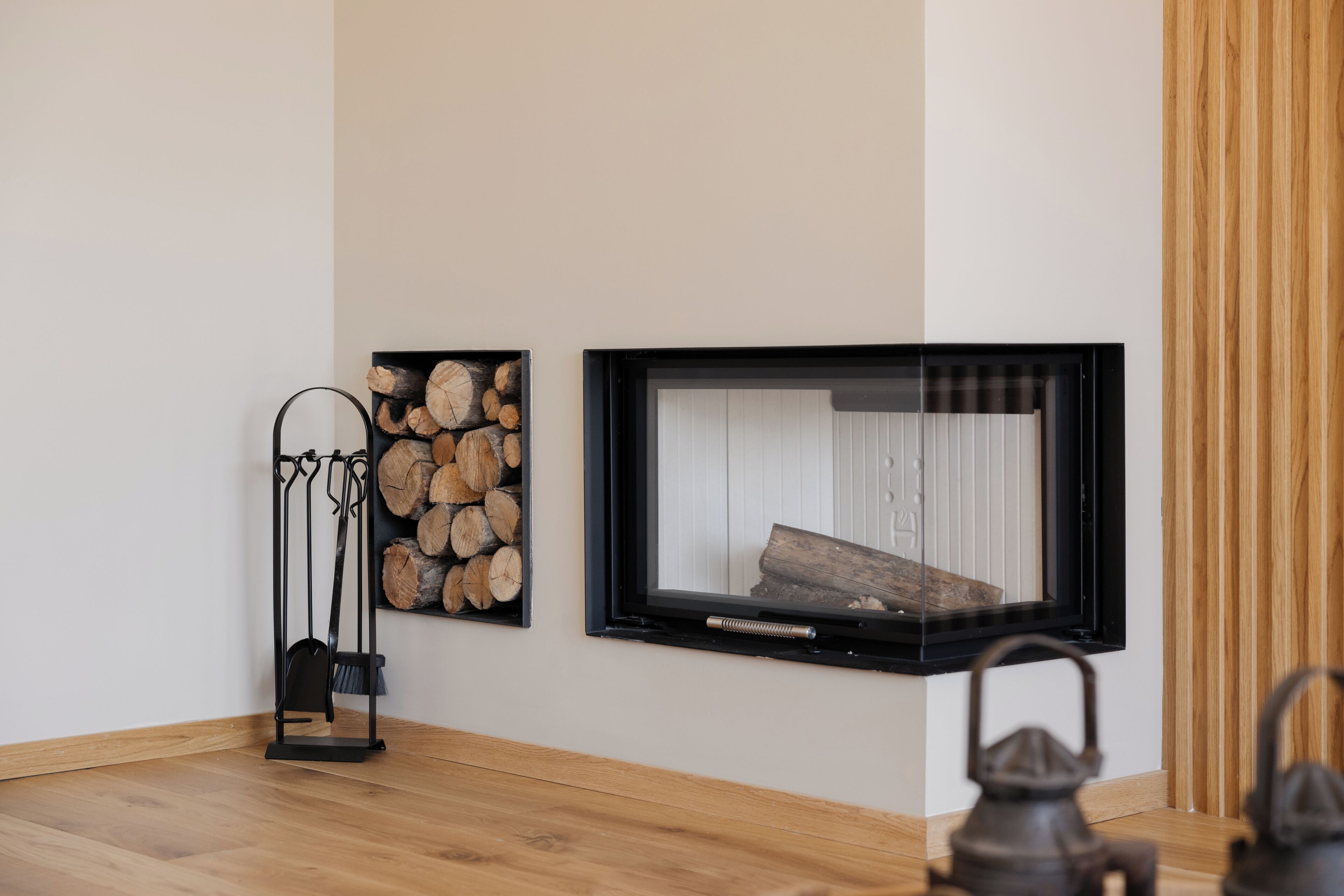 Una habitación con chimenea, una exhibición de leña en la pared y una lámpara de pie.