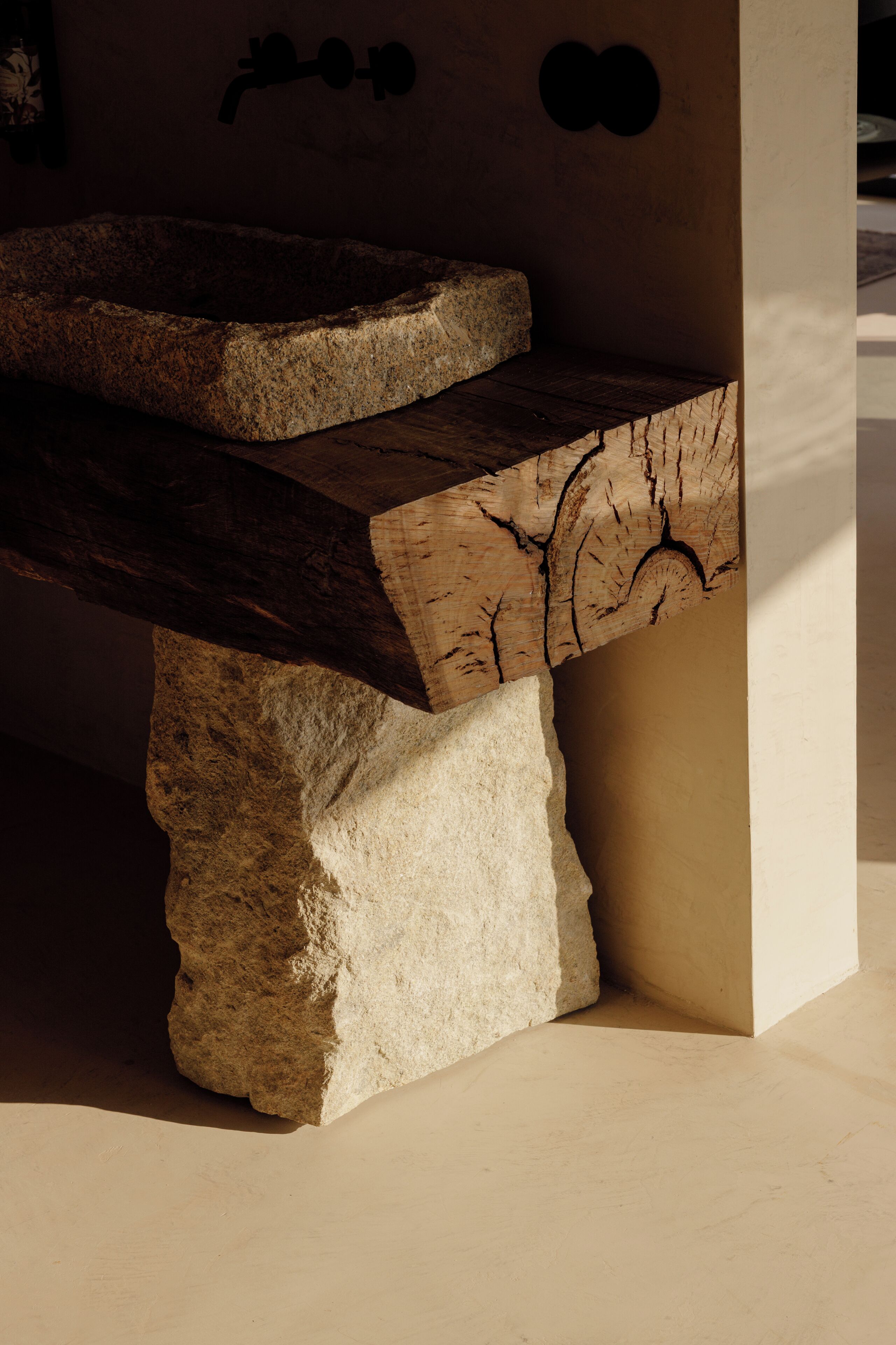 A stone bench with a natural wood finish, positioned against a wall with a simple, modern design.