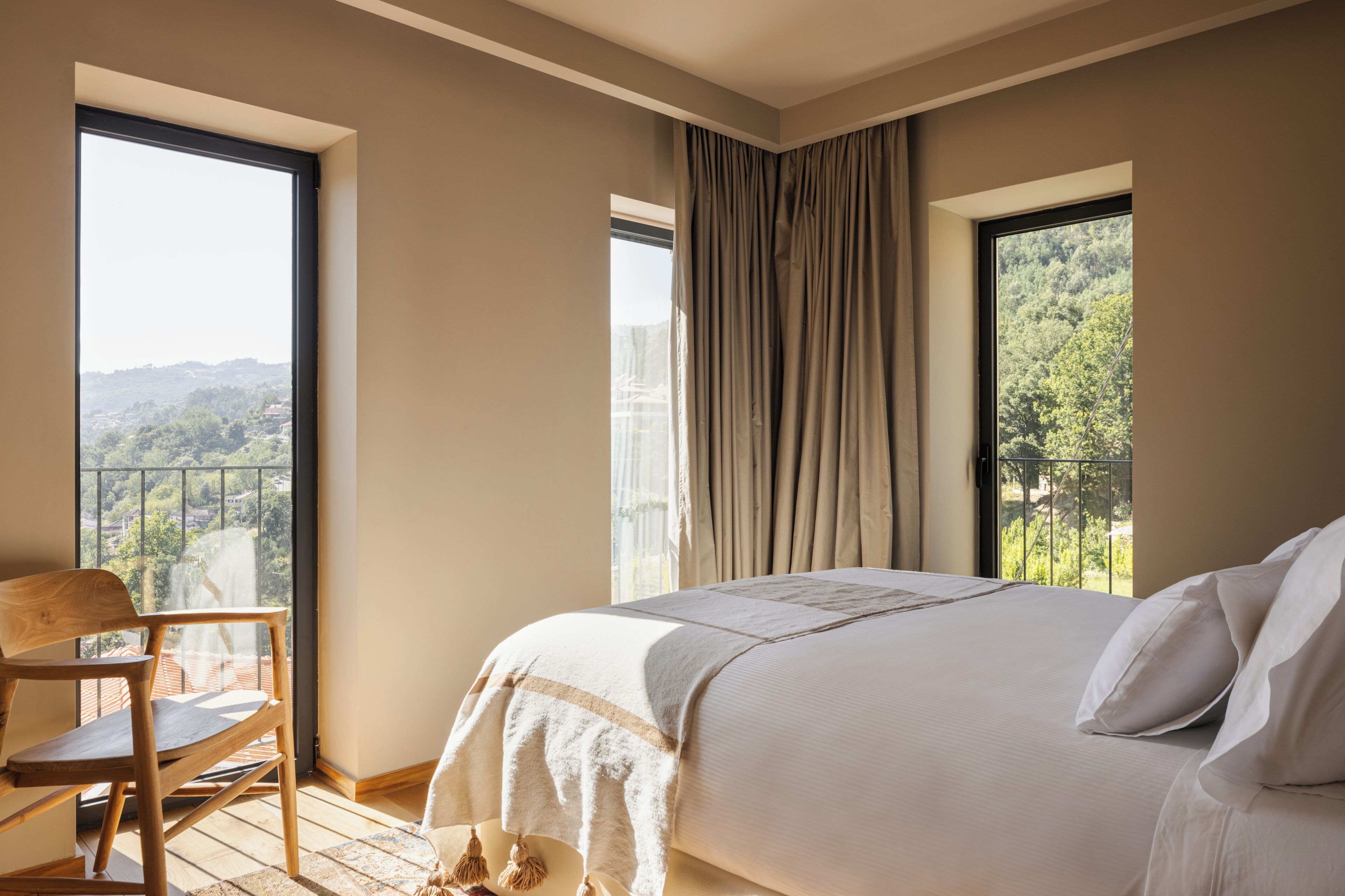 Une chambre à coucher avec un grand lit, une chaise et une vue sur le paysage urbain par la fenêtre.
