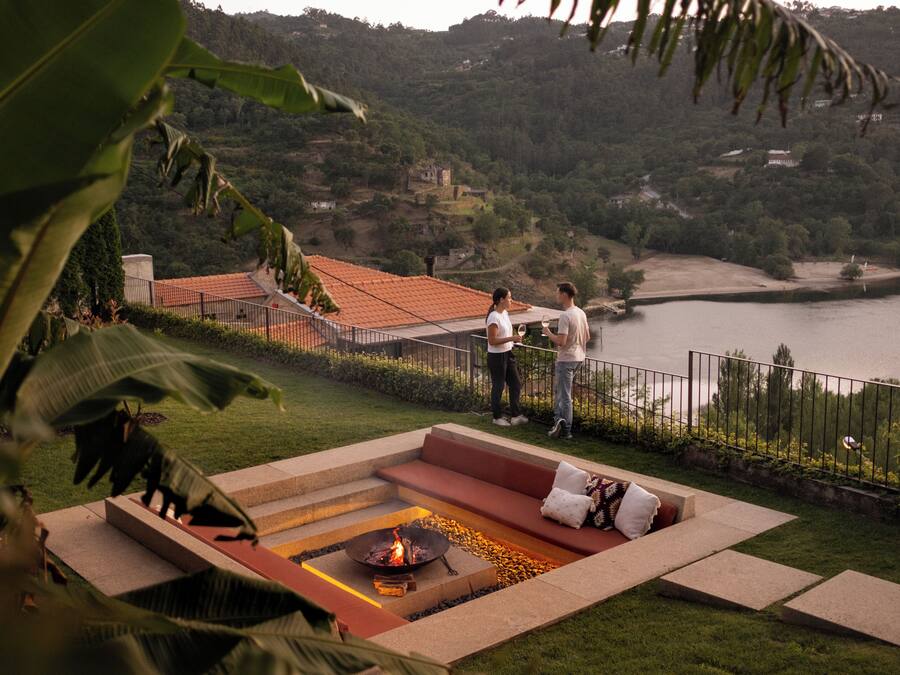A terrace with a fire pit, seating area, and a view of a lake and hills.