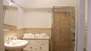 Een badkamer met een wastafel, spiegel en een douchecabine van glas.