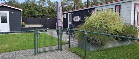 A fenced outdoor area with a paved walkway, a bench, and a small garden.