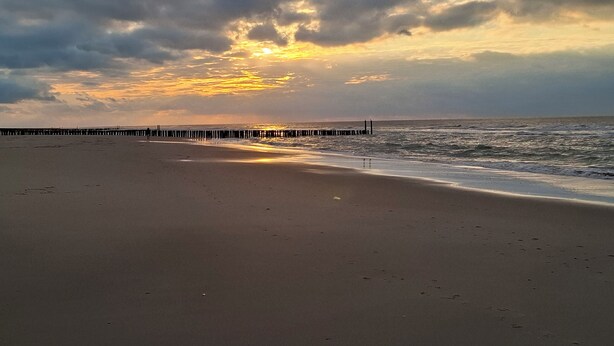 A beach with a wooden pier extending into the ocean, under a cloudy sky. - Pretty chalet with free WiFi on a friendly camping site (Serooskerke)