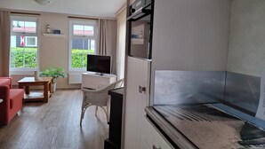 A compact living space with a kitchenette, a dining area, and a seating area with a red chair and a small table. - Pretty chalet with free WiFi on a friendly camping site (Serooskerke)