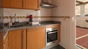 A kitchen with wooden cabinets, a stainless steel oven, and a tiled backsplash. - CT 100 - Antes Penthouse (Mijas)