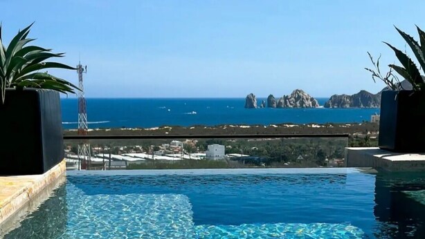 En klarblå pool med utsikt över havet och klippformationer i fjärran.