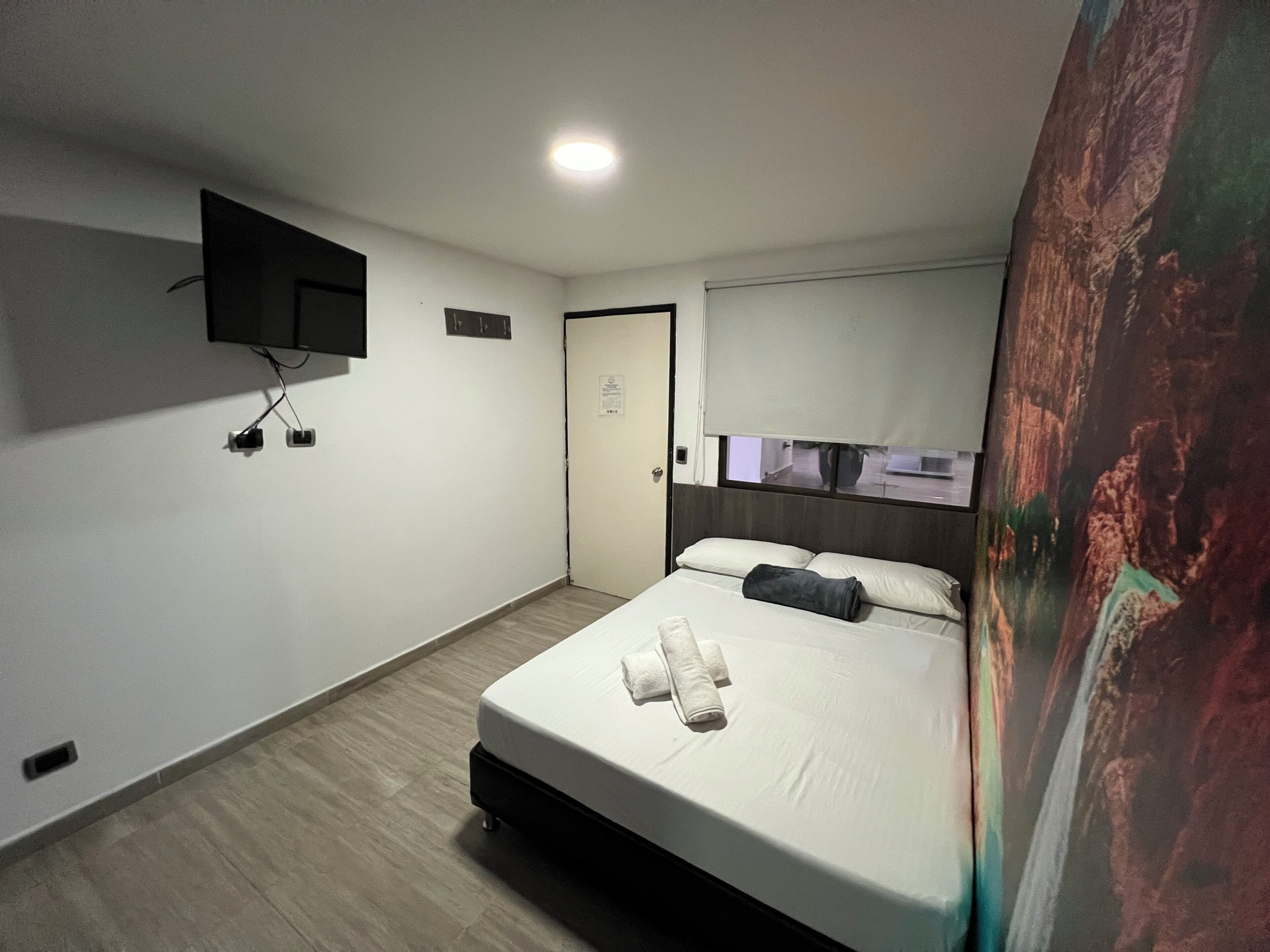 Une chambre à coucher comprenant un lit, un téléviseur à écran plat fixé au mur, une porte et une fenêtre donnant sur un paysage agréable.