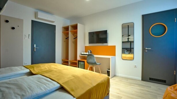 A modern bedroom with a bed, a desk, a chair, a wardrobe, and a television. - Ice Premium Apartments  (Veszprem)