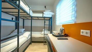 A bunk bed room with a desk, kettle, and power outlet.