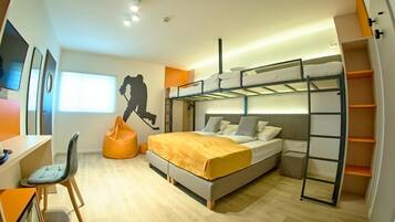 Quarto moderno com beliches, escrivaninha e poltrona de encosto.