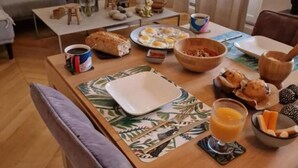 A breakfast setup with eggs, bread, and juice on a table in a living room with a sofa and coffee table in the background.