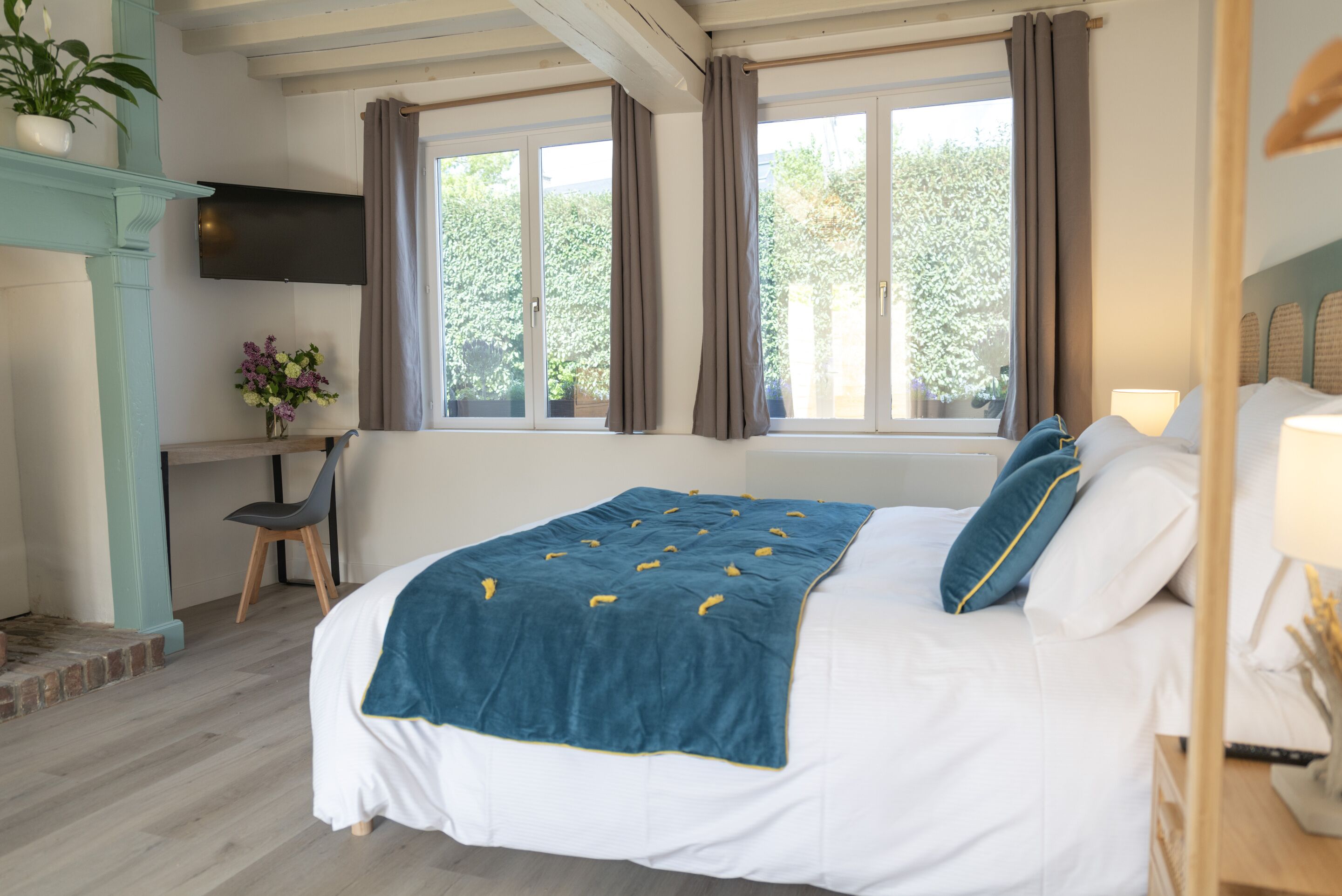 Un dormitorio con cama, escritorio, silla, televisor y ventana con cortinas.